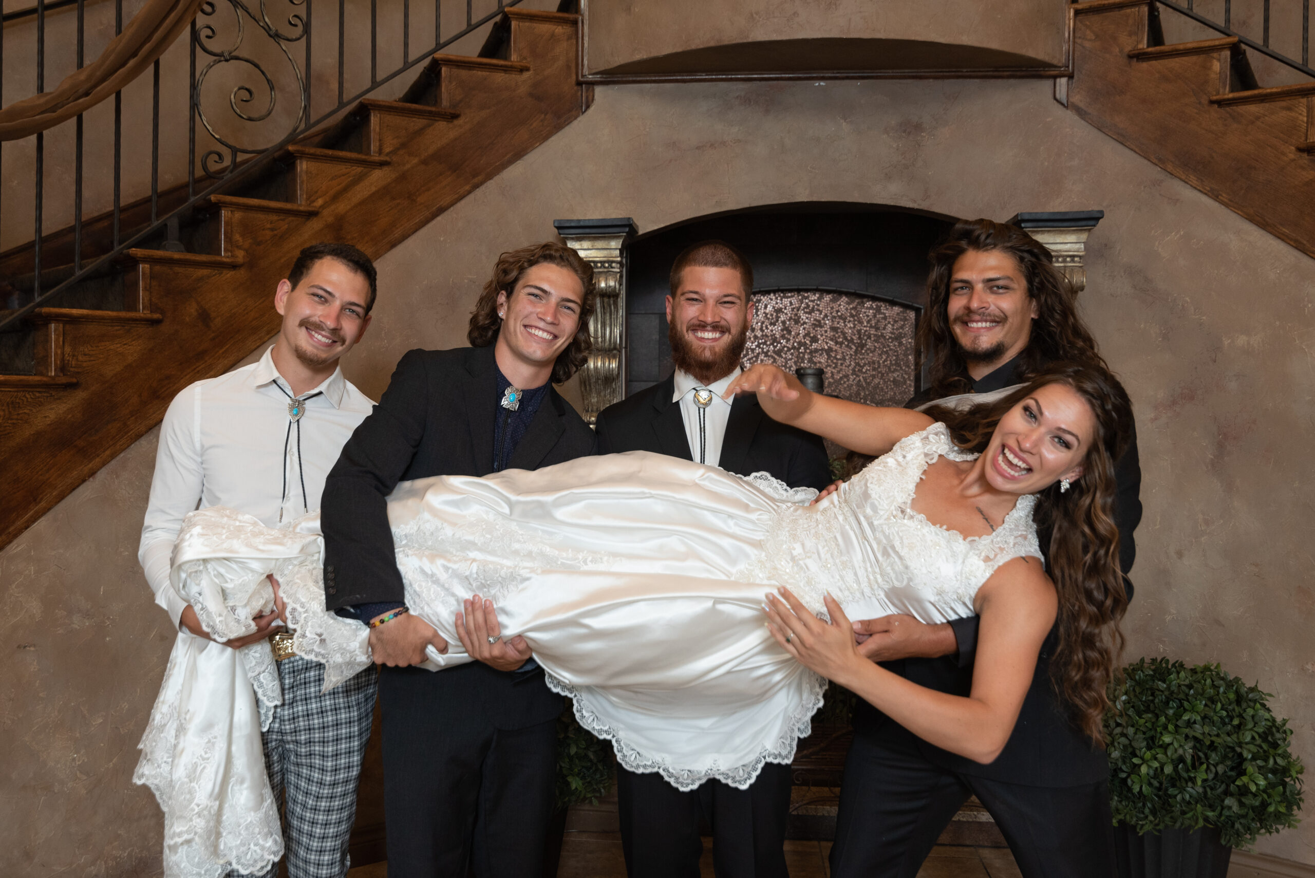 Sibling brothers holding up their sister on her wedding day.